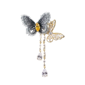 Broche papillon luxueuse avec pampilles et pierres en zircon sur un fond blanc épuré