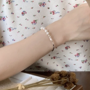 Detailed shot of half-pearl and silver geometric metal bracelet worn on wrist