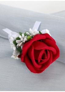 Macro detail of red velvet rose wrist corsage with white ribbon and decorative beads