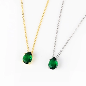Detailed comparison of pear-cut emerald pendants in gold and silver chains on white background
