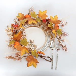Autumn wreath detail with maple leaves and pumpkins set on a festive dining table