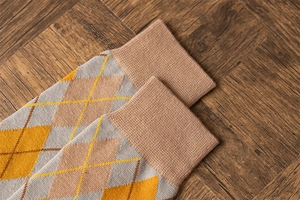 Close-up of vintage argyle knit knee high socks with elastic ribbed cuffs on wood floor