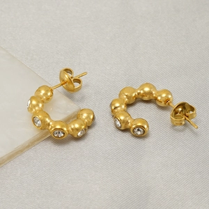 Boucles d'oreilles créoles dorées en C avec cristaux sur support en marbre