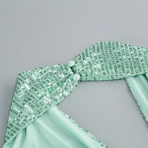 Macro detail of mint green sequins on mesh fabric with satin trim and fabric buttons