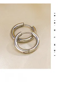 Macro shot of polished silver hoop earrings with hinged clasp on silk background