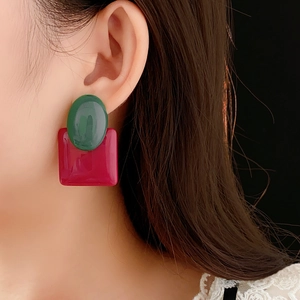 Detail of vintage resin earrings with green oval and magenta square geometric design