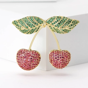 Macro shot of cherry brooch with micro-pave green and pink cubic zirconia and gold plating