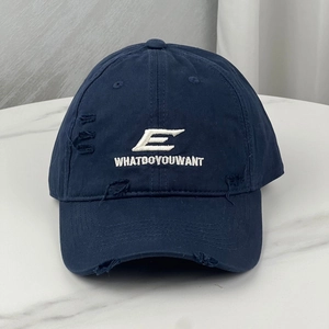 Close-up of navy blue baseball cap featuring white embroidery and distressed ripped details