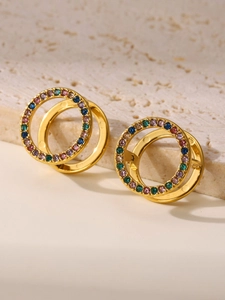 Detalle de pendientes chapados en oro PVD con piedras de circón de colores sobre piedra