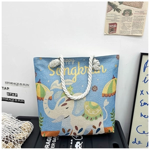 Close-up of elephant embroidery and Happy Songkran text on blue woven tote bag