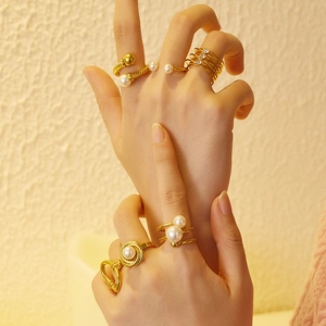Ensemble de bagues vintage dorées avec perles et zircons portées avec une lumière chaude