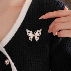Detail of 18k gold butterfly brooch with white mother-of-pearl and zircons on black knit