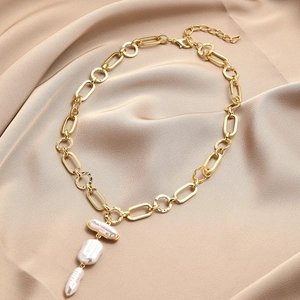 Detailed close-up of Baroque pearl necklace with gold metal chain on champagne silk