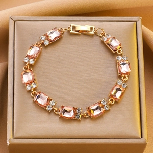 Dettaglio ravvicinato del bracciale con cristalli champagne su lussuosa seta dorata