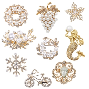 Set of 9 gold-tone floral and pearl brooches with rhinestones on a white background