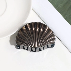 Detailed macro view of bronze shell hair claw with matte texture and gripping teeth