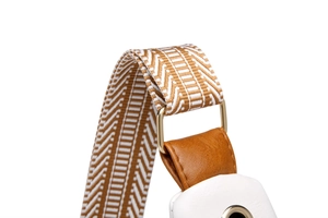 Detail of herringbone woven strap with gold metal buckle on a white leather chest bag