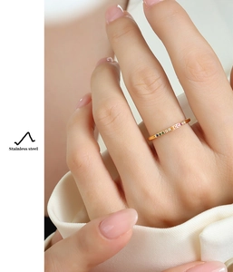 Detail of slim stainless steel gold ring with multicolored zircons on model's finger