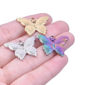 Détail des pendentifs papillons évidés en finitions dorée, argentée et arc-en-ciel