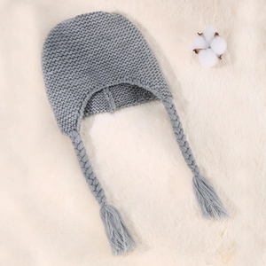 Close-up of grey cable knit baby hat with braided earflaps and tassel details