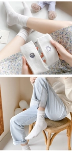 Detail of white cotton knee-high socks featuring cute animal embroidery and ribbed texture