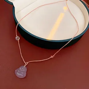 Violet chalcedony Buddha pendant on a light gold braided cord shown in an elegant box