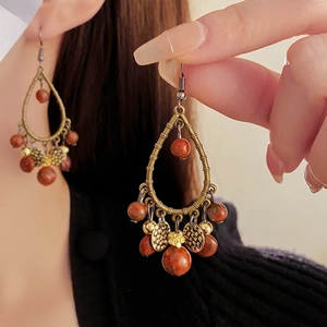 Close-up of Bohemian drop earrings with bronze metal tassels and reddish-brown beads