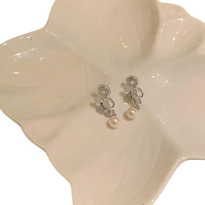 Elegant silver flower earrings with opal pearls and rhinestones on a white tray