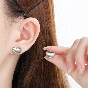Boucles d'oreilles cœur en acier brossé portées pour un style minimaliste chic