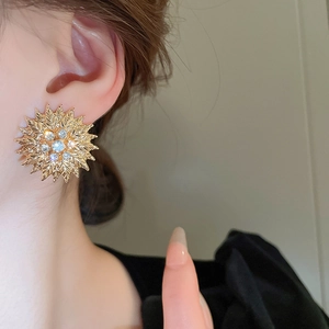 Gros plan de boucles d'oreilles tournesol dorées avec diamants portées au lobe de l'oreille