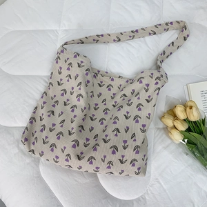 Close-up of beige corduroy tote bag featuring purple tulip prints and a long shoulder strap