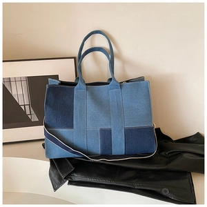 Detail of color-block denim tote bag with textured patchwork and woven shoulder strap