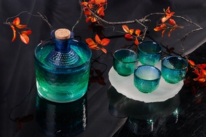 Detailed view of hammered blue glass sake set with carafe, cork stopper and matching cups