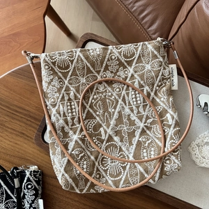 Detailed close-up of retro embroidered canvas bag with floral patterns on a wooden tray