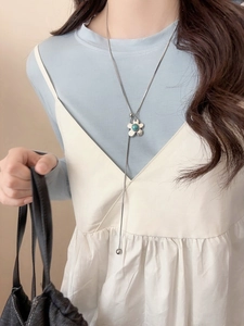 Detail of silver Y-shaped flower necklace with turquoise bead on a model's chest