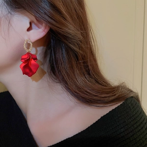 Detail view of red petal drop earrings with gold textured rings worn by a model