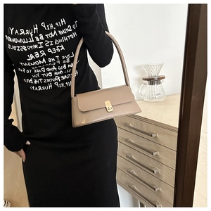 Minimalist beige baguette shoulder bag with gold square buckle shown in mirror reflection