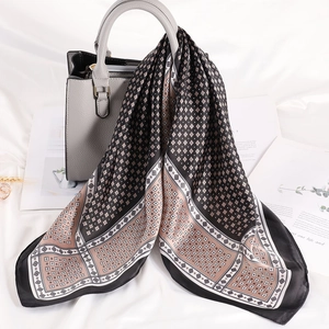 Dettaglio di un foulard in seta a righe geometriche annodato al manico di una borsa