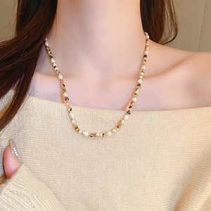 Detail of freshwater pearl and gold bead necklace worn by a model in knitwear