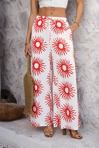Détail d'un pantalon large bohème blanc avec imprimé soleil rouge et cordon de serrage