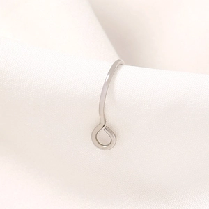 Polished silver stainless steel U-shaped nose ring on white silk background macro detail
