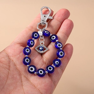 Detailed view of Evil Eye keychain featuring a blue eye bead and crystal palm charm in hand
