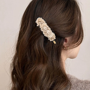 Close-up of vintage white pearl hair clip with varied sized pearls on hair