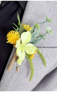 Detail of yellow lily boutonniere with green leaves pinned on a grey wool suit lapel