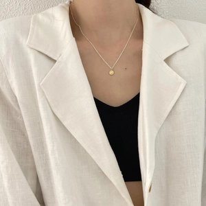 Close-up of minimalist 925 sterling silver coin necklace on a female model neck