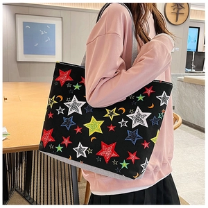 Detail of a large capacity black canvas tote bag with colorful stars and moon print