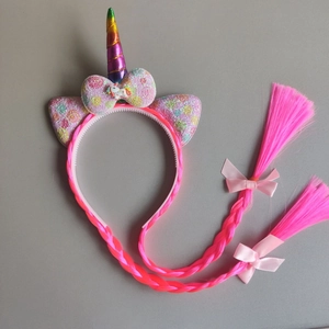 Detail of unicorn headband with rainbow horn, glittery ears, and pink braided hair extensions