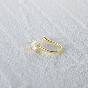 Detail of gold U-shaped nose cuff featuring a sparkling round zircon in a four-prong setting
