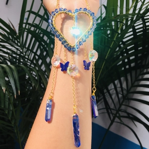 Macro view of handmade golden heart suncatcher with blue butterfly and crystal pillars