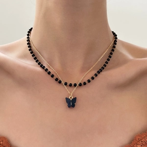 Gothic double-layer necklace featuring black beads and a butterfly pendant on a gold chain
